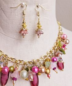 Make a statement with this one-of-a-kind floral charm necklace and earrings set. Gold wire wrapped freshwater pearls, glass pearls, cut Swarovski crystals, Czech glass flowers and leaves, gold plated findings, and assorted glass beads are hung on a gold-plated chain on the lower half of the necklace chain and finished with a matching lobster clasp.  This bright and colorful beaded necklace comes with all charms shown. Necklace length can be adjusted as requested, prior to checkout.  Matching floral earrings are hung on gold ear wires. Makes a great addition to your collection or a wonderful gift for someone special. Adjustable Multicolor Necklaces With Flower Charm, Bohemian Pink Necklace With Flower Charm, Elegant Flower-shaped Glass Necklaces, Multicolor Flower-shaped Jewelry With Charms, Pink Flower-shaped Necklaces With Colorful Beads, Flower Charm Necklace, Swarovski Crystal Necklace, Glass Flowers, Floral Earrings