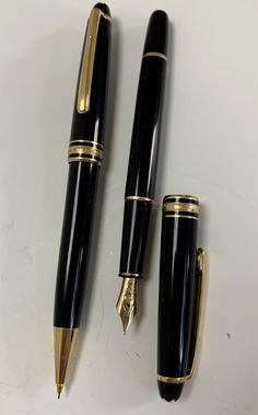 two black and gold fountain pens on a white surface