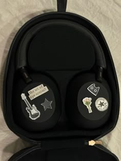 two black headphones in a case on a bed