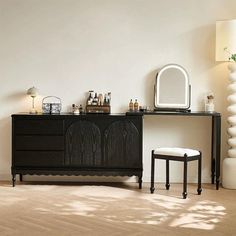 a white room with a black dresser and mirror