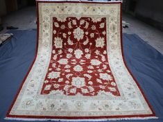 a large red rug is laying on the floor in front of a blue sheet that has been folded over it