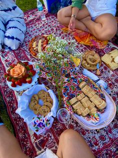 people sitting at a picnic table with food on it and flowers in vases next to them