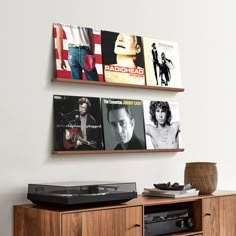 there are two wall mounted pictures on the wall next to a record player and an entertainment center