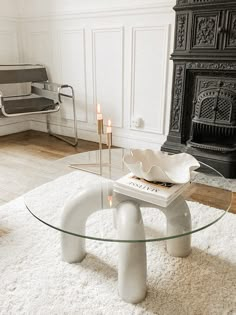 a living room with a glass coffee table and white rugs on the floor in front of a fireplace