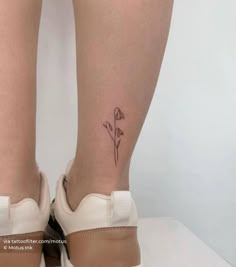 a woman's legs with a small flower tattoo on her left leg and the bottom part of her right leg