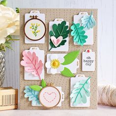 a close up of a greeting card with paper flowers and leaf shapes on it next to yarn