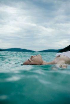 a woman floating in the ocean with her eyes closed