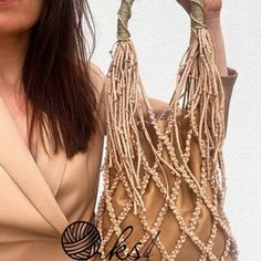 a woman holding up a purse with beads on it's handles and the bottom part of her hand