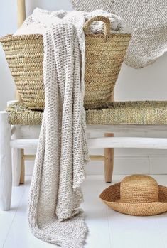 a chair with a blanket on it next to some baskets and a hat laying on the floor