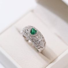 Featuring a heart-shaped emerald centerpiece surrounded by a dazzling halo of diamonds, this delicate ring embodies the essence of vintage elegance. The rich green color of emeralds symbolizes love and vitality, while sparkling diamonds add a touch of glamor. Metal: Recycled Sterling Silver Gemstone: Cubic Zirconia Ring Diameter: 10mm Weight: 7g