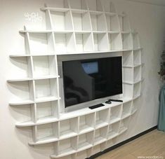 a white entertainment center with shelves and a flat screen tv mounted on it's wall