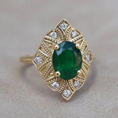 an emerald and diamond ring on a table