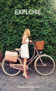 a woman standing next to a pink bicycle with the words explore on it's side