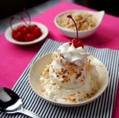 a dessert dish with whipped cream and cherries on the top, served in small bowls