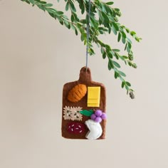 a felt ornament hanging from a tree branch with leaves and other things on it