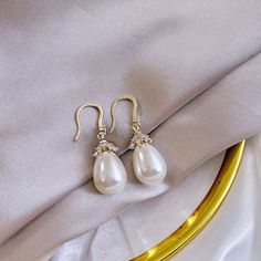 Best of both worlds! Iridescent pearls and clear cubic zirconia that capture the light from every angle with a perfectly translucent appeal come together to create a classy, sparkly and elegant pair of bridal earrings. The settings are gold / rhodium plated for a bright finish which enhances the intricate detailing and conveys a modern take on old elegance. Overall length of the earring is 1.5" (approx. 3.8cm). Width: 0.4" (approx. 1.2cm). Weight: 6g. Available in Yellow Gold and Silver with Whi Luxury Yellow Gold Pearl Bridal Earrings, Elegant Diamond White Crystal Earrings, Diamond White Crystal Pearl Earrings, Elegant White Pearl Embellished Earrings, Elegant Pearl Embellished Cubic Zirconia Earrings, White Pear-shaped Party Jewelry, White Pearl Drop Crystal Earrings, White Crystal Pearl Drop Earrings, White Pearl Drop Earrings With Crystal