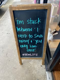 a chalkboard sign that says i'm stuck between i need to save money and you only live once