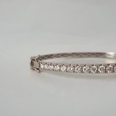 This stunning diamond bangle is a classic design that can be worn for any events. Featuring over a total of approximately 2 carat natural white diamonds framed in 14K and 18K solid gold. The bangle has a slightly tapered band creating a feminine look. Put together with a box clasps and a safety hinge. Handcrafted in 14K Yellow gold, rose gold and white gold. Model is wearing 6.5" bracelet. 14K or 18K solid gold 25 Natural white brilliant cut diamonds. SI clarity GH color, Approx 2 ct total carat White Gold Diamond Cut Bangle Bracelet, Classic Diamond White Bangle Hand Set, Classic Hand Set Diamond White Bangle, Formal White Gold Diamond Chain Bracelet, Elegant Moissanite Diamond Bracelet Hand Set, Luxury Brilliant Cut Bangle For Anniversary, Classic Diamond Bangle For Anniversary, Timeless Platinum Bangle Diamond Bracelet, Timeless Diamond Bangle Bracelet