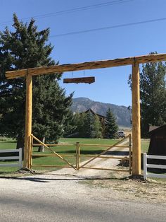 a wooden gate is open on the side of a road