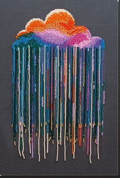 an art work with beads hanging from it's sides and clouds in the background