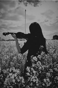 a woman is playing violin in a field