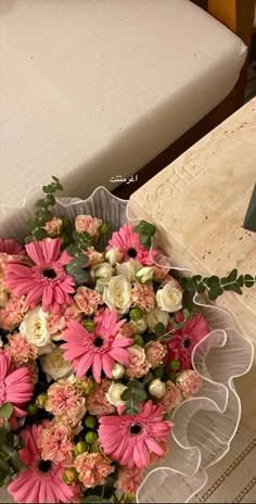 a bouquet of pink and white flowers sitting on top of a table next to a mattress