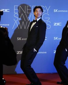 a man in a tuxedo poses on the red carpet at an awards ceremony