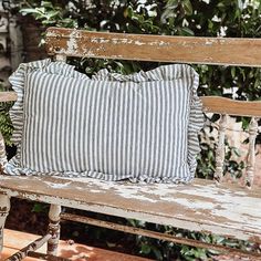 a striped pillow sitting on top of a wooden bench next to a potted plant