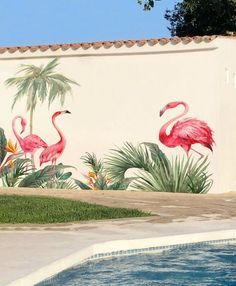 two flamingos painted on the side of a wall next to a pool