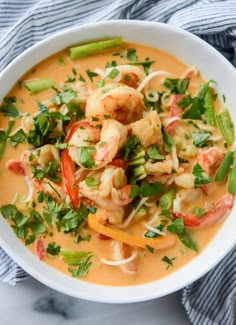 a white bowl filled with shrimp and veggies on top of a blue towel