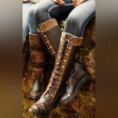 a woman sitting on top of a rock wearing tall brown boots with lace - up sides