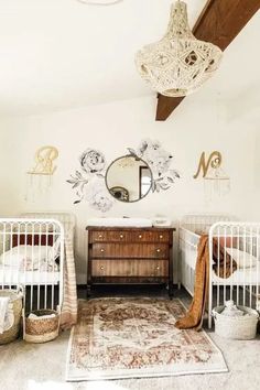 two cribs in a white nursery with floral wall decals