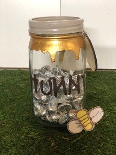 a jar filled with lots of candy sitting on top of a green grass covered floor