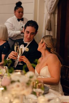 a man and woman sitting at a table with champagne glasses