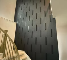 a stair case in front of a black wall with vertical lines painted on the side