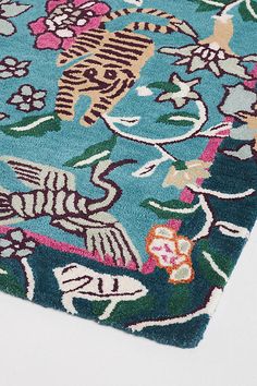 a blue rug with colorful flowers and birds on the top is laying on a white surface