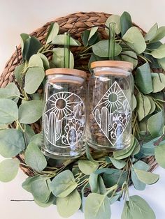 two mason jars sitting next to each other on top of a basket filled with leaves