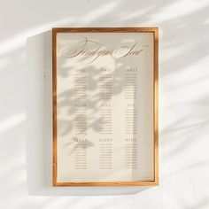 a wedding seating chart hanging on a wall with shadow from the sun coming through it