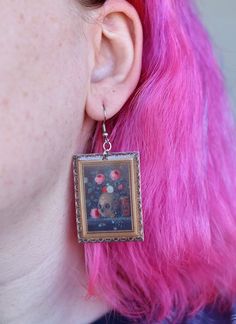 These fine art earrings depict a still life painting of a skull and vibrant florals with an ornate gold frame by Jan Van Kessel the Elder in 1670.  These unique drop earrings are the perfect gift for a witch, art lover, Halloween lover, painter, or history buff in your life. Wear them to a party, class, or to a museum! (Or anywhere else for that matter) These earrings are made of acrylic, an epoxy layer, and hypoallergenic nickel-free stainless steel earring hooks.  You will receive:  1 pair of Dark Academia Earrings, Academia Earrings, Artist Earrings, Vanitas Still Life, Painting Earrings, Frame Earrings, Skull And Flowers, Artistic Earrings, Gothic Floral