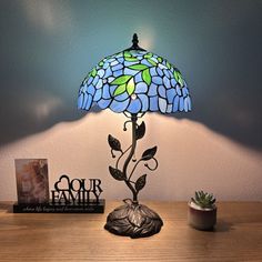 a lamp that is sitting on top of a table next to a book and plant