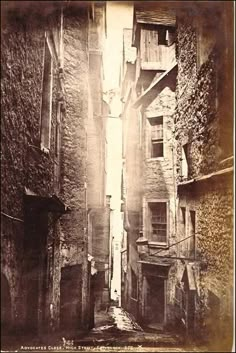 an old black and white photo of a narrow alleyway with buildings on both sides