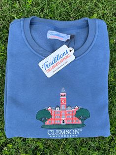 Show your school spirit in this super soft cotton-polyester blend sweatshirt. The tight, clean embroidery on the chest pops with the iconic campus building logo. The ribbed collar, cuffs, and hem add structure and style to this cozy crewneck top. Whether heading to an early morning class or late night game, this sweatshirt allows you to display your college pride in casual comfort. The durable fabric ensures this classic embroidered college sweatshirt will remain a staple in your rotation for years. Embroidered College Sweatshirt, Building Logo, University Crewneck, Clemson University, College Sweatshirt, School Spirit, Early Morning, Late Night, Sweat Shirt