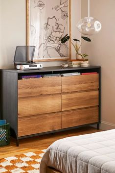 a bedroom with a bed, dresser and pictures on the wall