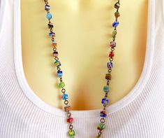 a woman wearing a white shirt and necklace with multicolored beads hanging from it