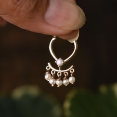 a close up of a person's hand holding a pair of earrings with pearls