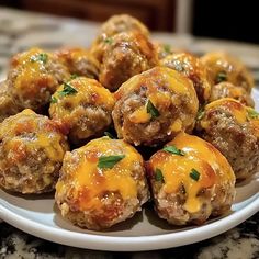 a white plate topped with meatballs covered in cheese and parsley on top of a marble counter