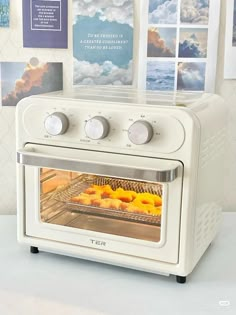 a white toaster oven sitting on top of a counter with pastries in it