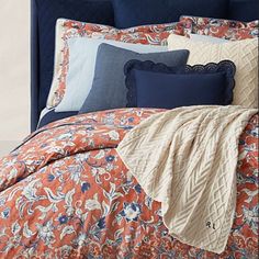 an orange and blue bed with pillows and blankets