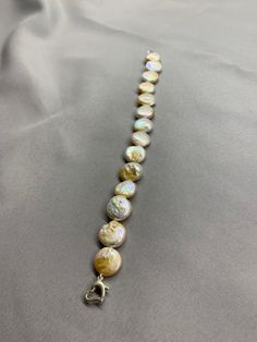 White and Champagne Coin Pearl Bracelet. This bracelet features 14 ea White and Champagne Freshwater Baroque Coin Pearls A+ with high luster 12-13mm and a 925 silver heart clasp. The bracelet measures 7 1/2 inches while laying flat. I hand knotted this with spectra thread. It holds up better than silk and is stronger. It does not stretch, hold oils, and can be gotten wet. I have been using it for years with good results, but only on my freshwater pearls and especially for bracelets. We have some White Round Single Strand Bracelet, White Bracelet With Sterling Silver Clasp For Anniversary, White Bracelets With Sterling Silver Clasp For Anniversary, Formal Beaded Bracelet With Sterling Silver Clasp, White Single Strand Round Bracelet, Single Strand Bracelet, Adjustable Single Strand Pearl Bracelet, White Bracelets With Sterling Silver Clasp And Round Beads, Silver Single Strand Pearl Bracelet