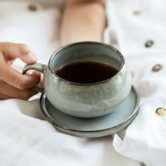 a person holding a cup of coffee on top of a saucer